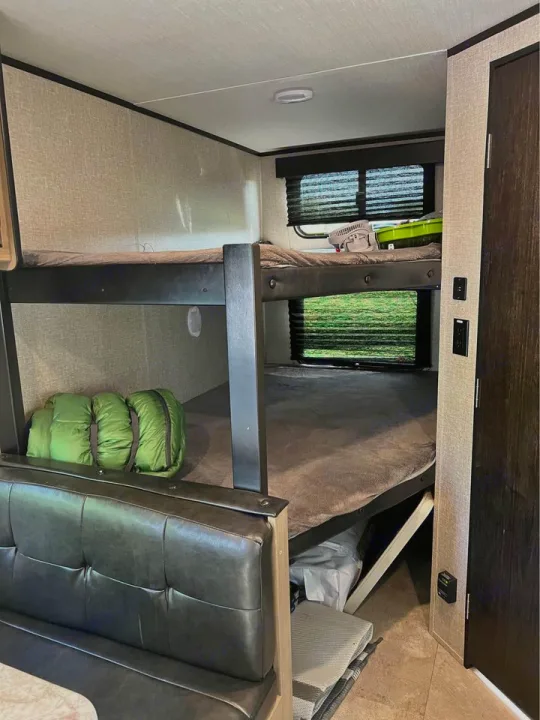 Inside an RV rental: cozy bunk beds, a dinette bench, and storage for gear. Ideal for family adventures.. Grand Design Transcend Xplor 2020