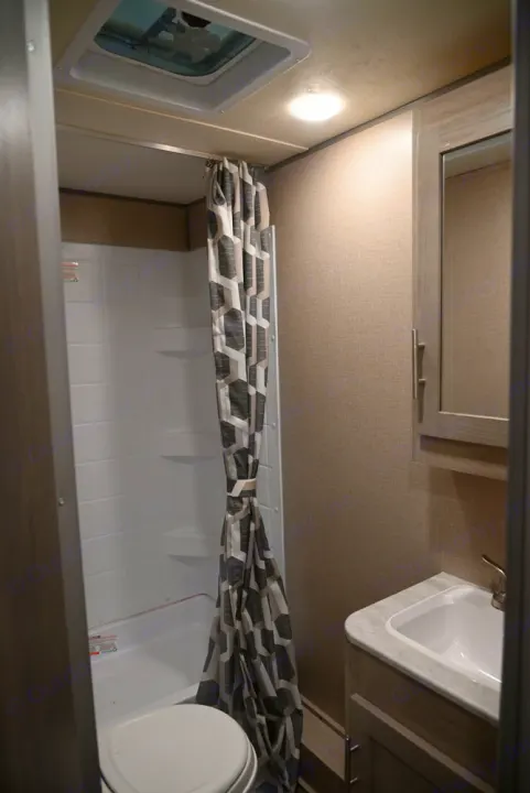 RV rental bathroom featuring a compact shower, toilet, sink, overhead lighting, and ceiling vent for comfortable travel.. Coachmen Catalina Summit 184BHS 2022