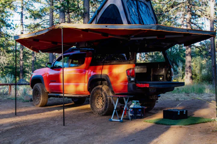 Red Toyota Tacoma truck with deployed rooftop tent and awning. A versatile overland camp setup, an alternative to an RV rental.. Toyota Tacoma TRD Pro 2023