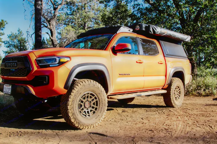 Orange Toyota Tacoma, an off-road overlanding beast with rooftop tent & canopy. Perfect for your adventure-ready RV rental.. Toyota Tacoma TRD Pro 2023