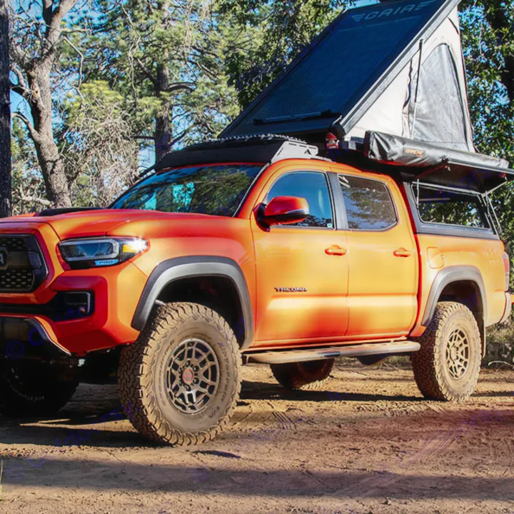 An orange Toyota Tacoma overlander, equipped with a rooftop tent & awning. A ready RV rental for your next outdoor adventure.. Toyota Tacoma TRD Pro 2023