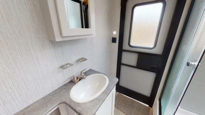 Compact RV rental bathroom: Features a sink, vanity, medicine cabinet, and shower area for comfortable travel.. Forest River Palomino Puma 2023