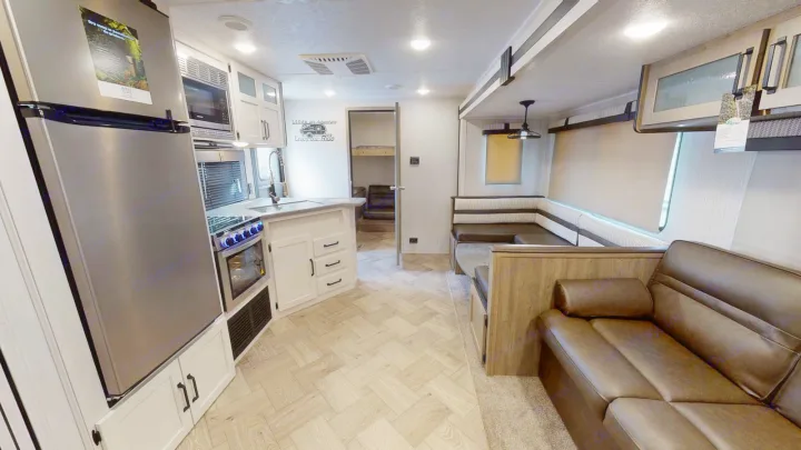 Modern RV rental interior featuring a stainless kitchen, comfy dinette, sofa, and bunk beds for family travel.. Forest River Palomino Puma 2023