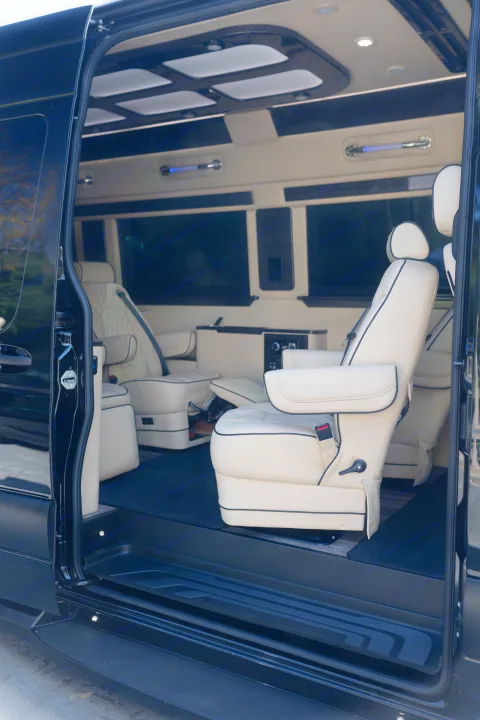 Experience luxury in this RV rental's custom van interior. View the premium cream captain's chairs, elegant lighting, and lounge setup.. Ultimate Toys Ultimate Coach 2023