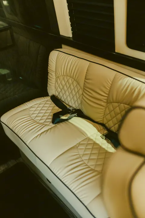 Experience comfort in our RV rental! Quilted cream leather seats with seatbelt and dark wood paneling.. Ultimate Toys Ultimate Coach 2023