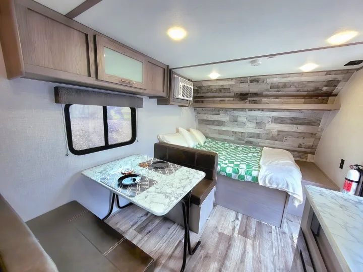 Bright RV rental interior with a cozy dinette, comfortable bed area, and modern decor.. Coleman Lantern 2023