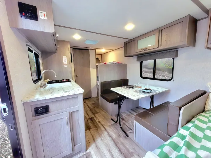 Spacious RV rental interior featuring a modern kitchenette, comfortable dinette, and bright living area, ideal for travel.. Coleman Lantern 2023