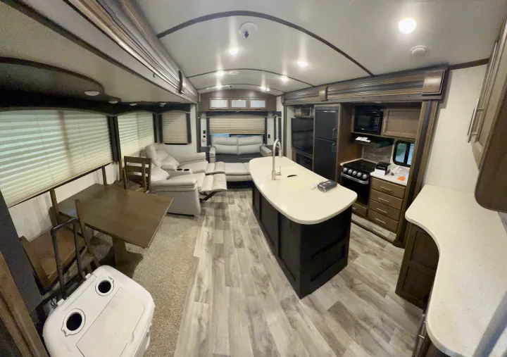 Spacious RV rental interior with modern kitchen island, dining area, and cozy living space.. Keystone RV Cougar 2019