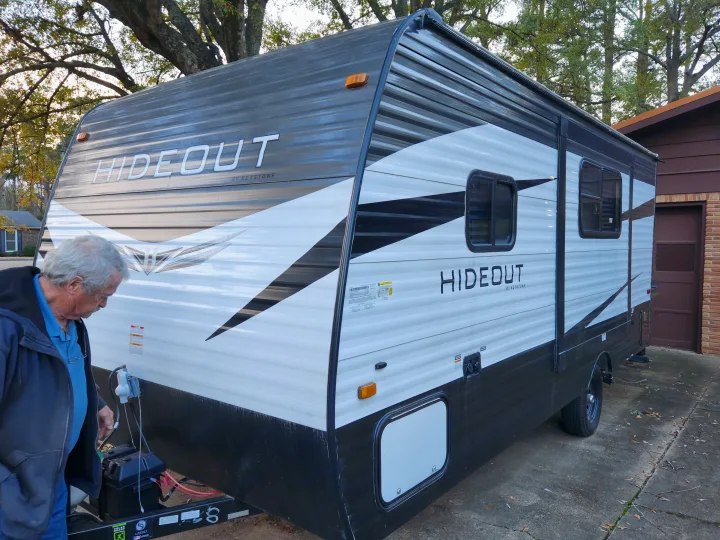 A man prepares a white and black Hideout travel trailer for an RV rental.. Keystone RV Hideout 2021