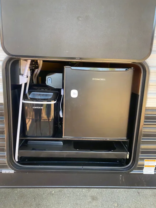 This RV rental's exterior compartment offers a mini-fridge and ice maker, essential amenities for convenient outdoor living.. Forest River Cherokee Grey Wolf 2021