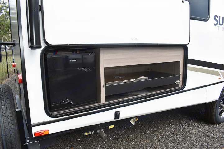 This RV rental features an outdoor kitchen with a Hotpoint fridge and a pull-out cooking tray.. Crossroads RV Sunset Trail Super Lite 2023