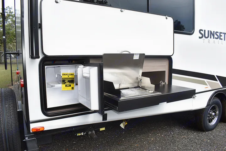This RV rental offers an exterior kitchen with a mini-fridge, pull-out grill, and counter area, ideal for outdoor living.. Crossroads RV Sunset Trail Super Lite 2023