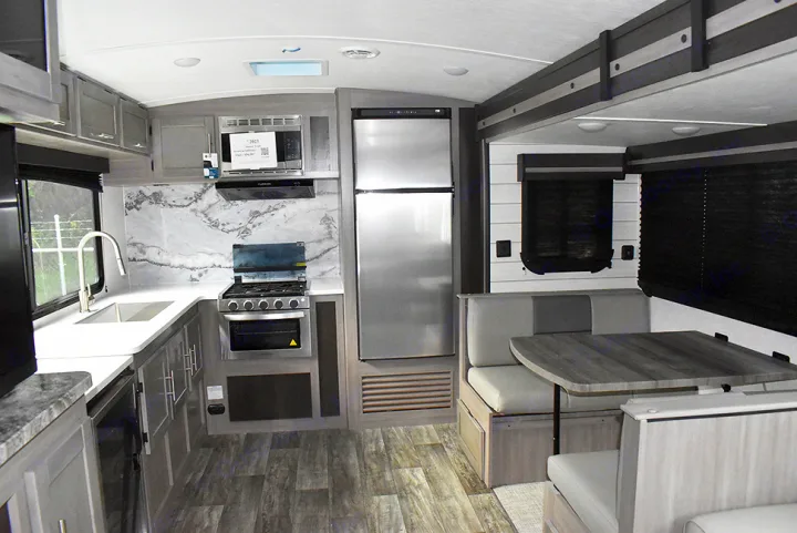 Modern RV rental interior with full kitchen, stainless steel fridge, and comfortable dinette for your travels.. Crossroads RV Sunset Trail Super Lite 2023