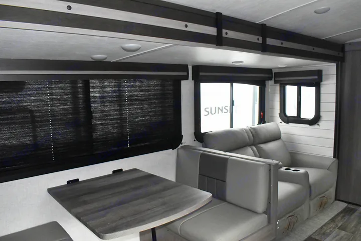 Spacious RV rental interior featuring a cozy dinette, comfortable theater seating, and dark blinds for mobile living.. Crossroads RV Sunset Trail Super Lite 2023
