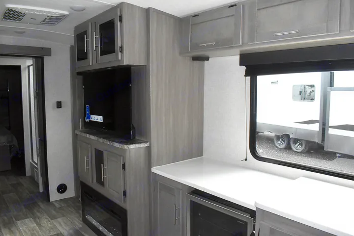 Modern RV rental living area featuring TV, fireplace, kitchen counter with appliances, and cabinetry. Enjoy comfort on the road.. Crossroads RV Sunset Trail Super Lite 2023