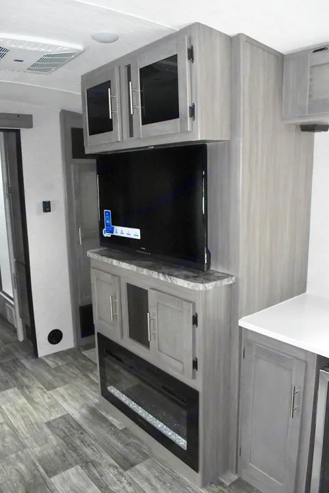Modern RV rental interior features a prominent entertainment center with a large TV, electric fireplace, and storage cabinets.. Crossroads RV Sunset Trail Super Lite 2023