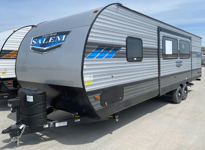 A new gray Forest River Salem travel trailer with blue graphics, ideal for rv rental trips. Parked on concrete under a clear sky.. Forest River Salem 2022