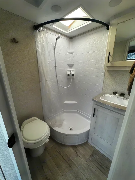 Compact RV rental bathroom featuring a corner shower, toilet, and vanity sink, ideal for on-the-go travel.. Dutchmen Coleman Rubicon 2021