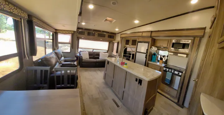 Spacious rv rental interior showing living room w/ sofa, modern kitchen with island, and appliances. Bright, clean design.. Atlas Atlas Fifth Wheel 2019