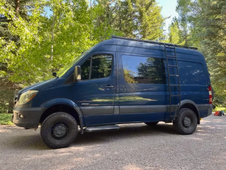 Dark blue, off-road equipped camper van with roof rack and ladder, ready for your next rv rental adventure.. Mercedes Sprinter 2016