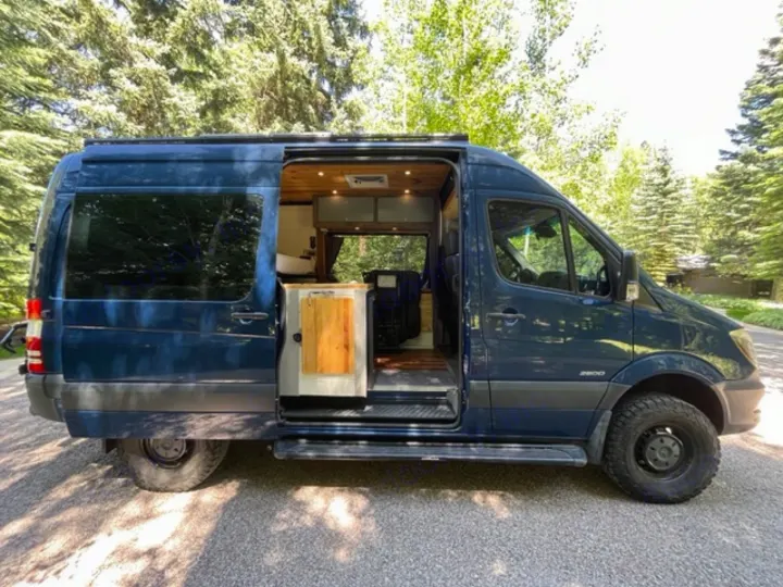 Dark blue Sprinter camper van rv rental with open door, revealing a cozy wood interior.. Mercedes Sprinter 2016
