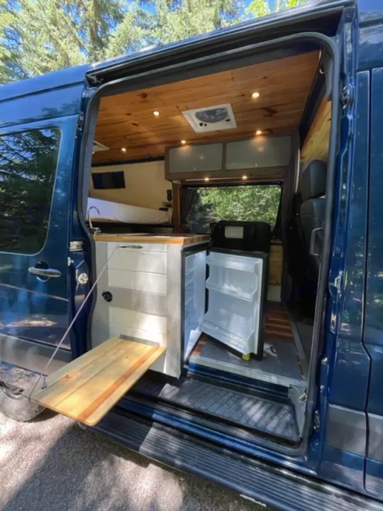 Tour an rv rental! See this custom camper van's interior: wood walls, built-in bed, and open fridge.. Mercedes Sprinter 2016