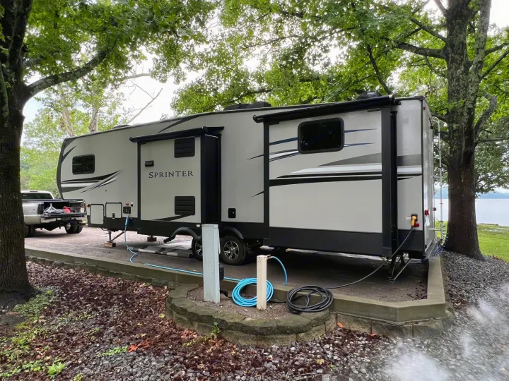 This SPRINTER RV rental is set up at a scenic lakeside campsite under trees, hooked to utilities.. Keystone RV Sprinter Campfire Edition 2020