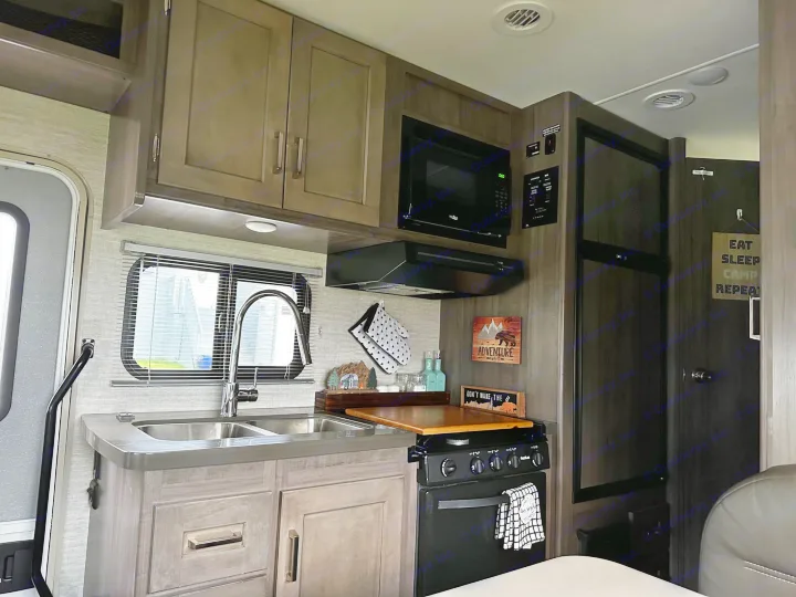 RV rental interior features a well-equipped kitchen with sink, stove, microwave, and fridge. Ready for travel.. Winnebago Minnie Winnie 2020