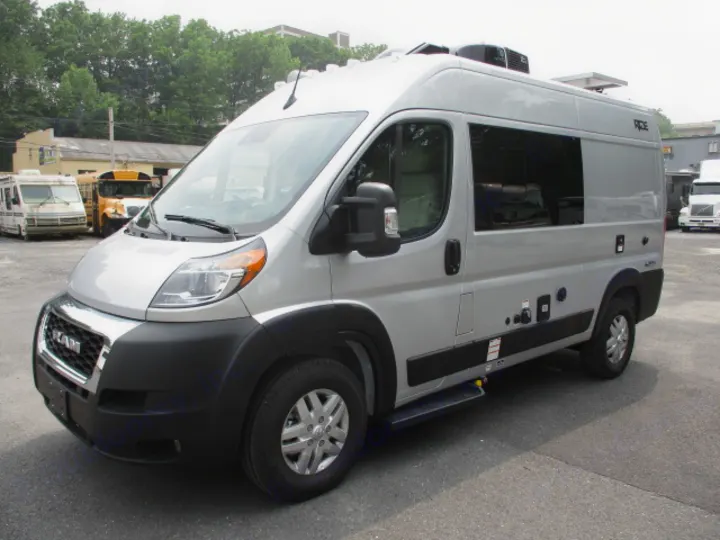 High-top silver Ram ProMaster rv rental van with AC unit, parked in a lot, ready for your next adventure.. Thor Motor Coach Rize 2023