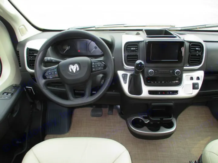 Modern RV rental interior: dashboard, Ram steering wheel, infotainment screen, and gear shift, ready for adventure.. Thor Motor Coach Rize 2023