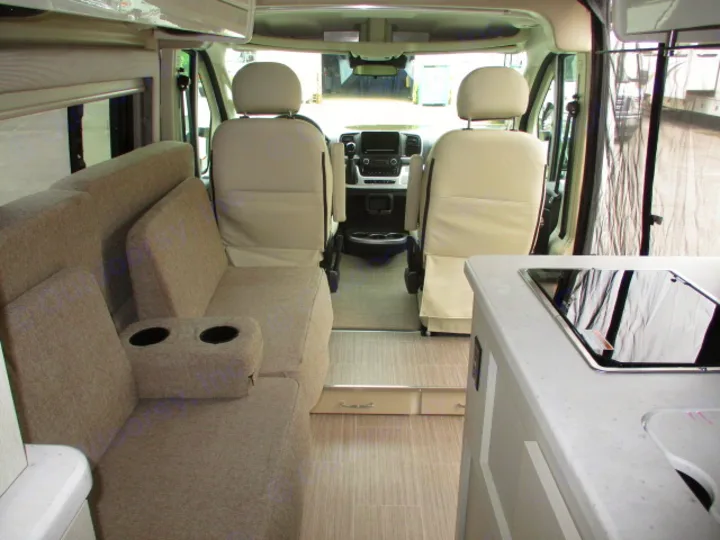 Explore this RV rental's interior: plush gray lounge, front swivel seats, and a built-in kitchenette with stovetop.. Thor Motor Coach Rize 2023