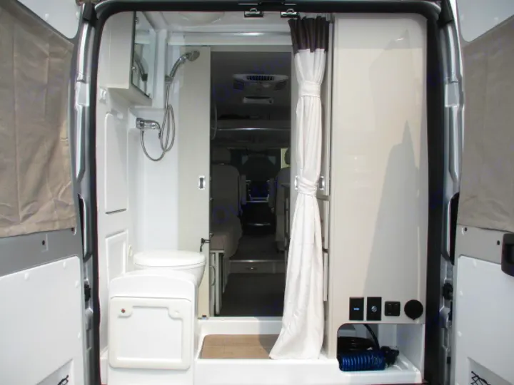 RV rental interior: A compact camper van bathroom, featuring a shower and toilet, viewed from the open rear doors.. Thor Motor Coach Rize 2023