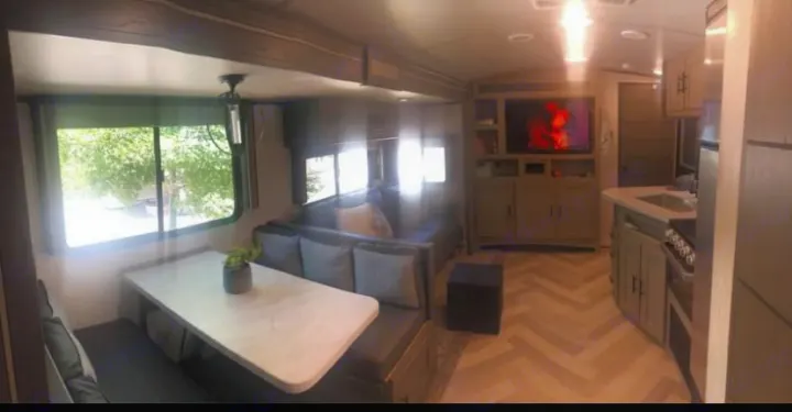 Modern RV rental interior: large living area with dining, couch, TV, and full kitchen, featuring herringbone flooring.. Cruiser Rv Corp Twilight 2021