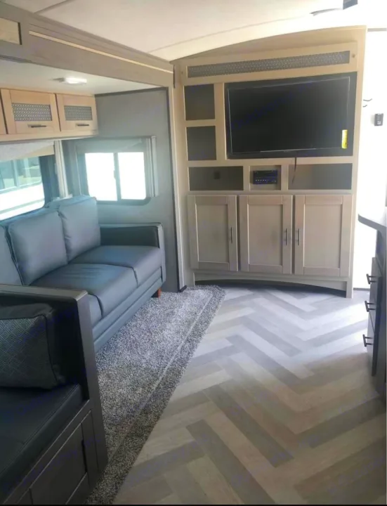 Experience comfort in this RV rental! Features a gray sofa, entertainment center with TV, and herringbone floor.. Cruiser Rv Corp Twilight 2021