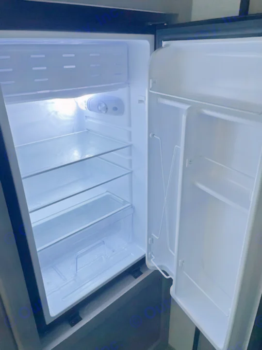 Open, empty compact fridge in an RV rental, ready for your journey's provisions.. Dutchmen Coleman Lantern LT 2023