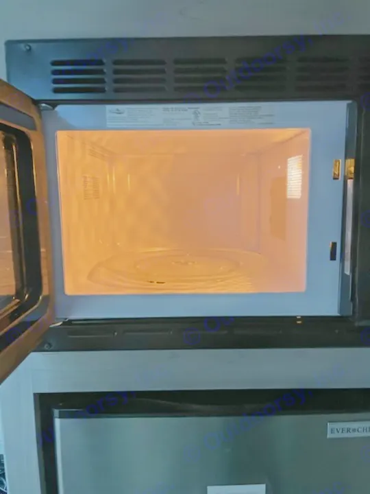 Interior of a microwave oven in an rv rental, with the door open and the light illuminating the turntable.. Dutchmen Coleman Lantern LT 2023