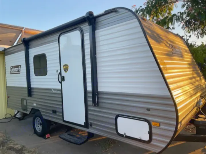 Side view of a white and gray Coleman travel trailer with an extended awning. Ideal for an RV rental adventure.. Dutchmen Coleman Lantern LT 2023