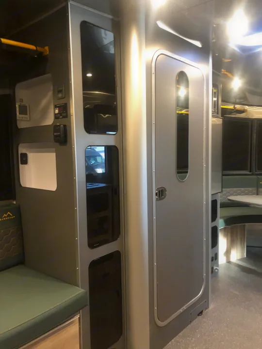 Modern Basecamp RV interior showing integrated control panel, storage cubbies, and dinette seating. Perfect for your next RV rental adventure.. Airstream Basecamp 2022