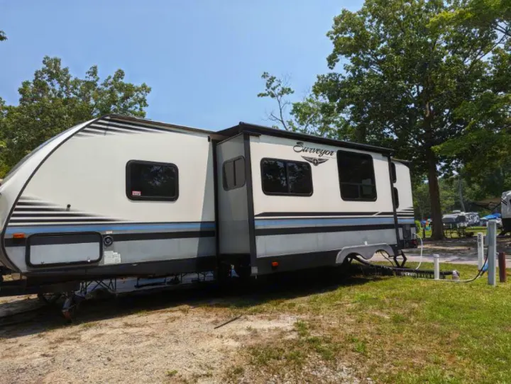 This RV rental, a Surveyor travel trailer, is set up at a shaded campsite with full hookups.. Forest River Surveyor 2017