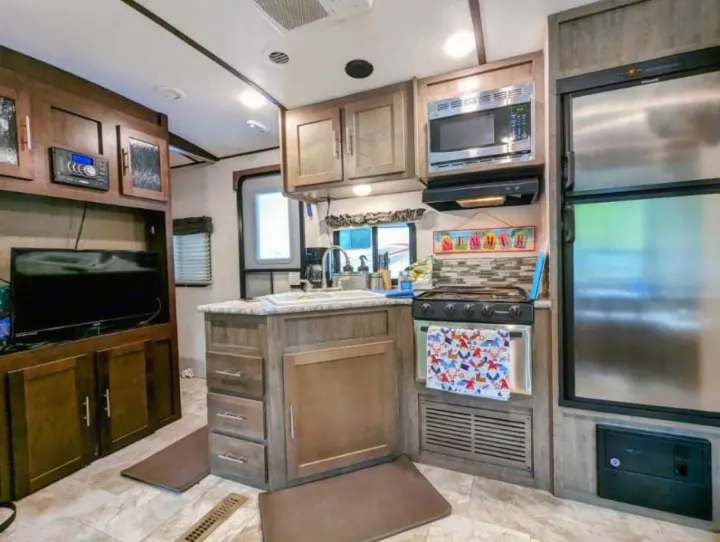 RV rental interior: well-equipped kitchen with stove, microwave, fridge, and entertainment center.. Forest River Surveyor 2017