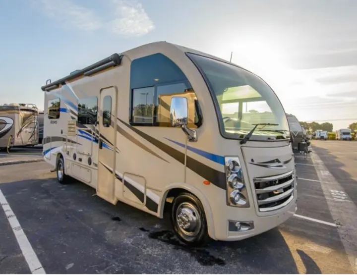 Experience adventure with this spacious RV rental, a Class C motorhome parked in a lot under a warm sky.. Thor Vegas 2018