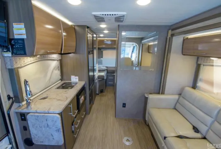 Inside an rv rental: functional kitchen, light wood cabinets, cozy sofa, and a compact living space, perfect for adventurers.. Thor Vegas 2018