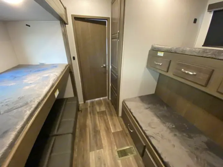 RV rental bunkhouse layout with two sets of bunk beds, hallway, bathroom door, and built-in storage.. Keystone RV Cougar 32BHS 2021