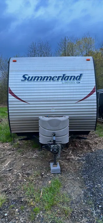 Front view of a white Summerland by Springdale travel trailer RV, ready for your next rental adventure outdoors.. Keystone RV Summerland 2015