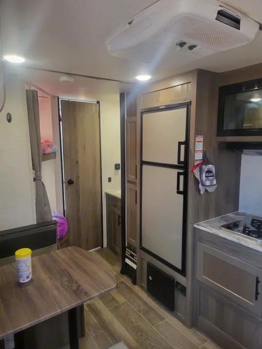 RV rental interior: kitchen with appliances (fridge, microwave), dining table, AC unit, and bunk beds.. Gulf Stream Enlighten 2021