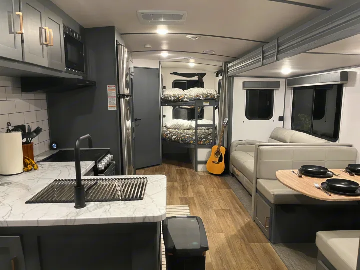 Modern rv rental interior: kitchen, bunk beds, and dining booth. Perfect compact living space for travel adventures.. Keystone RV Bullet Ultra Lite 2022
