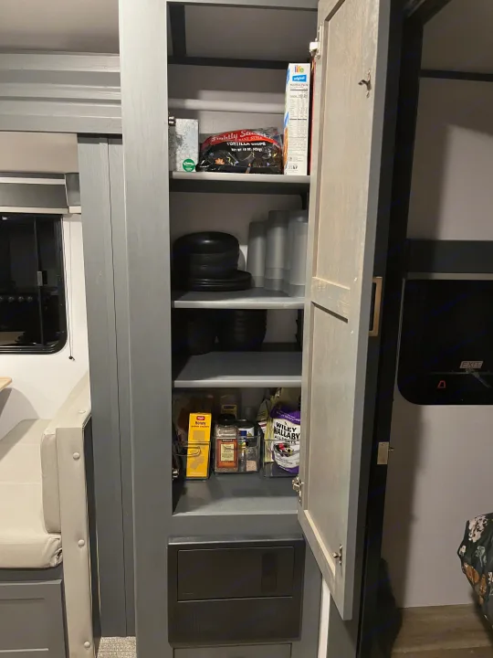 RV rental kitchen pantry with organized food items, dishes, and travel essentials for a comfortable journey.. Keystone RV Bullet Ultra Lite 2022