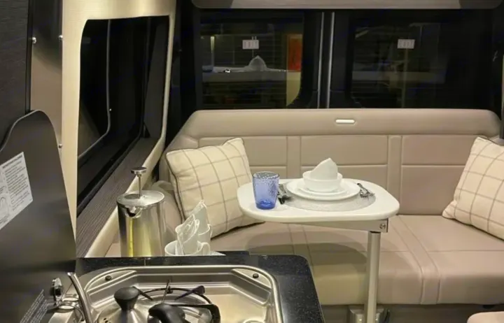 Step inside this RV rental, showcasing a functional kitchen, cozy dining area, and comfortable bench seating.. Airstream Interstate 2022
