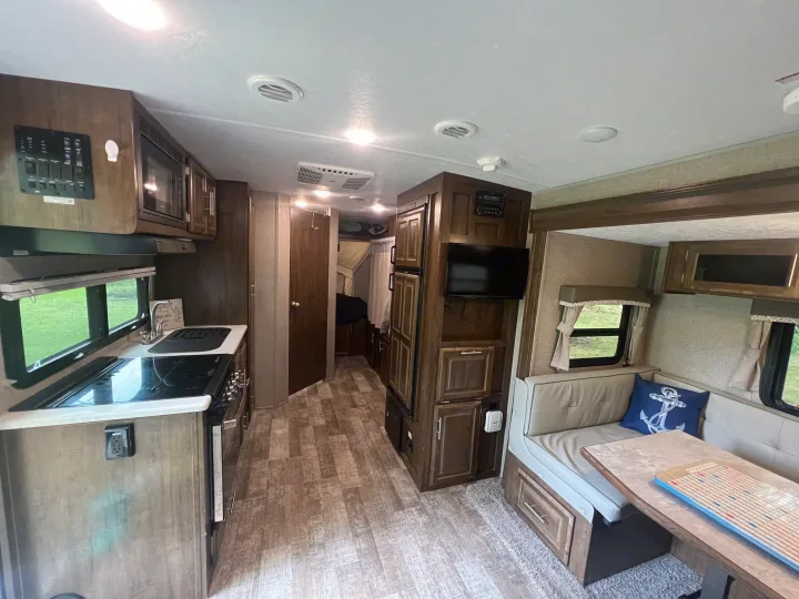 Spacious RV rental interior with full kitchen, dining booth, and TV.. Forest River Rockwood Roo 2019
