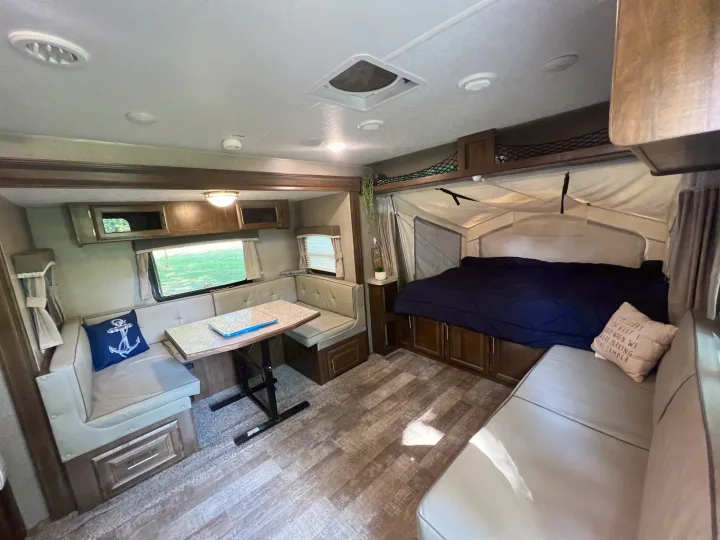 Explore this inviting rv rental interior, showcasing a cozy pop-out bed, dinette, and sofa area for comfortable adventures.. Forest River Rockwood Roo 2019